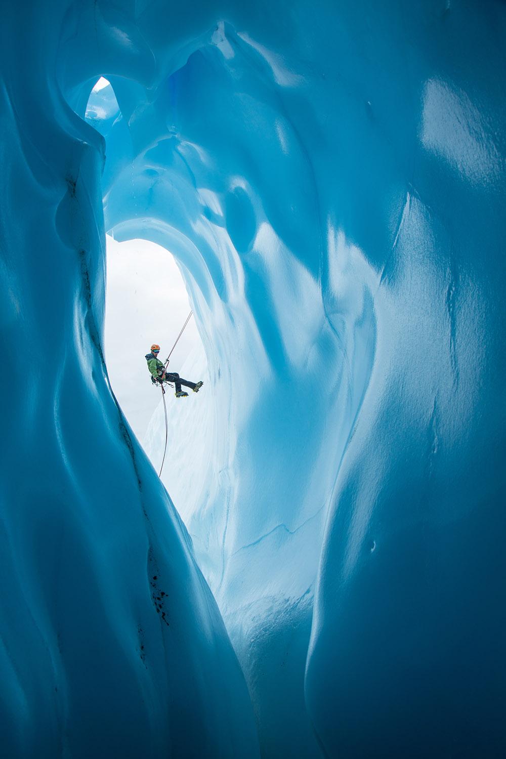 An,Ice,Climber,In,A,Green,Jacket,And,Orange,Helmet